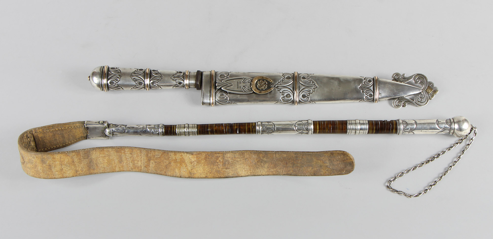 Lotes 594 y 595: 
																		IMPORTANTE CUCHILLO CINCELADO OBRA DEL PLATERO CUENCA.
																		REBENQUE CRIOLLO O LATIGO DE MONTAR CINCELADO.